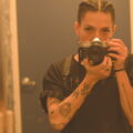 Ale Pedraza Buenahora's headshot depicts them holding a camera, obscuring the lower half of their face, pointed at a mirror to show their reflection.