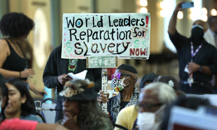 A man holds up a sign that reads "World Leaders, reparations for slavery now!"