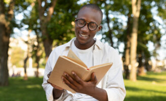 Student reading a book with nature in the background