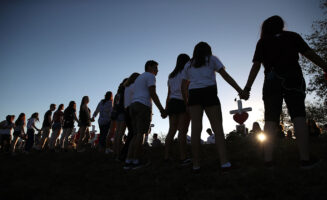 Photo of students holding hands at a vigil for a school shooting.