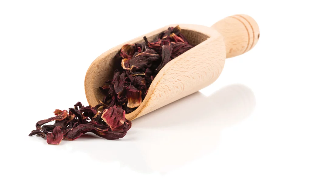 A wooden scoop holds dried hibiscus leaves.