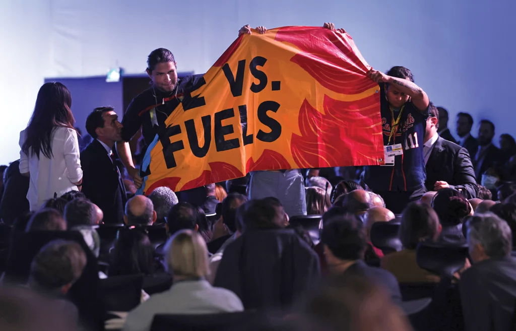 Big Wind Carpenter unfurls an orange and red banner, along with another activist, during Joe Biden's speech at the 2022 COP27 conference in Egypt.
