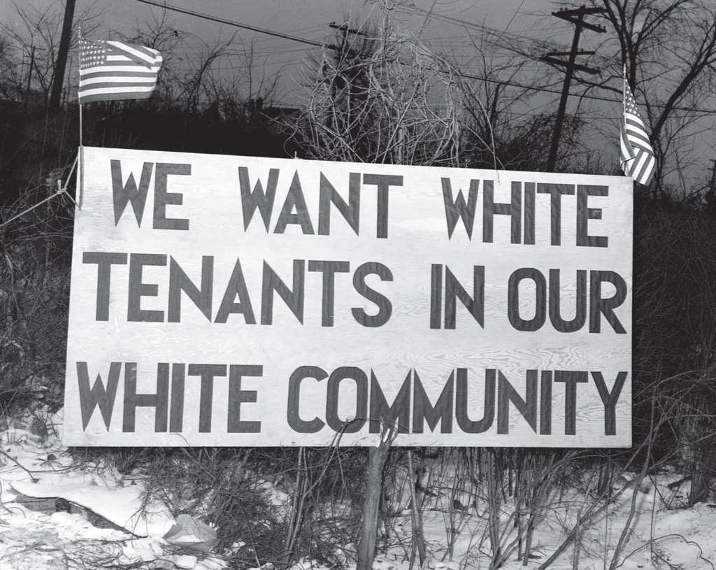 "We want white tenants in our community," reads large print on a 1942 sign constructed by white Detroit residents wanting to keep Black tenants from moving into a local federal housing project. 