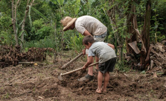Pedro Dos Santos, a Landless Workers Movement member, tills dirt with a young person on Dos Santos' land in Brazil.