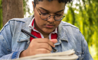 A photo showing afro-american woman writing notes in the woods.