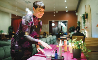 Bex Mui, founder of House of Our Queer, organizes items—including candles, water, oils, and talismans—on an altar table in preparation for a monthly "moon magic" ritual hosted at the interfaith, LGBTQ-affirming space in Oakland, California.