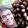 Marc van der Sterren, a white man with short brown hair and glasses, hugs a bundle of bananas.