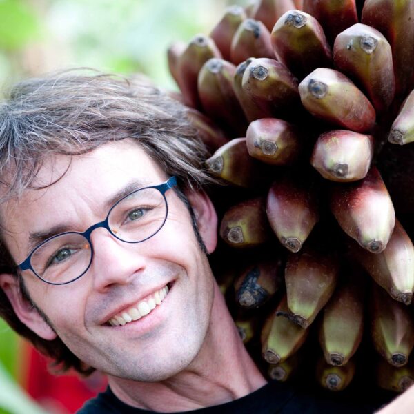 Marc van der Sterren, a white man with short brown hair and glasses, hugs a bundle of bananas.