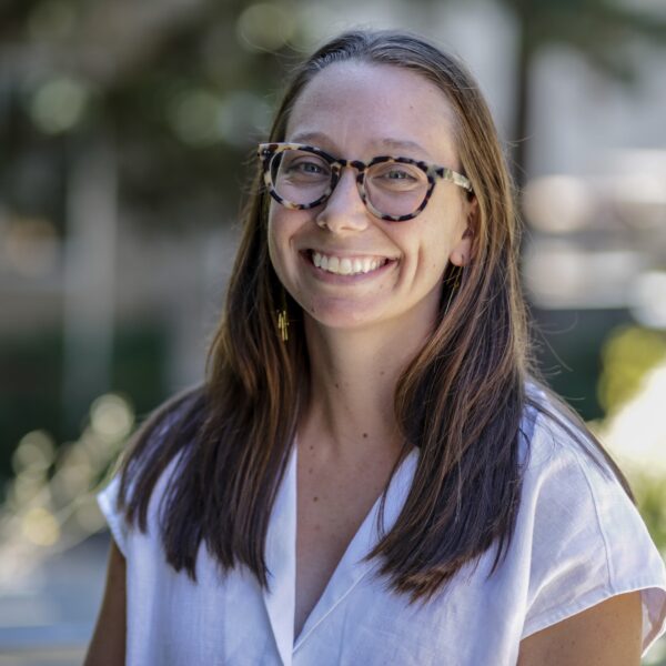 a white woman with brown hair and glasses smiles at the camera