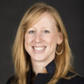 a white person with red hair looks and smiles at the camera