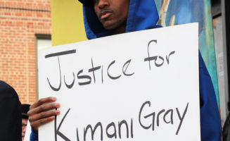 Man with Sign that reads “Justice for Kimani Gray”