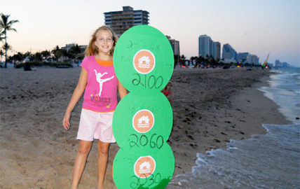 A girl holds sea level markers. Photo by 350.