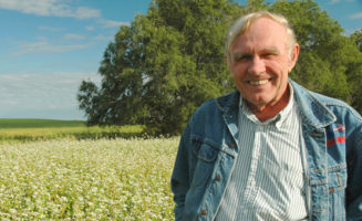 Fred Kirschenmann stands in a field.