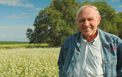 Fred Kirschenmann stands in a field.